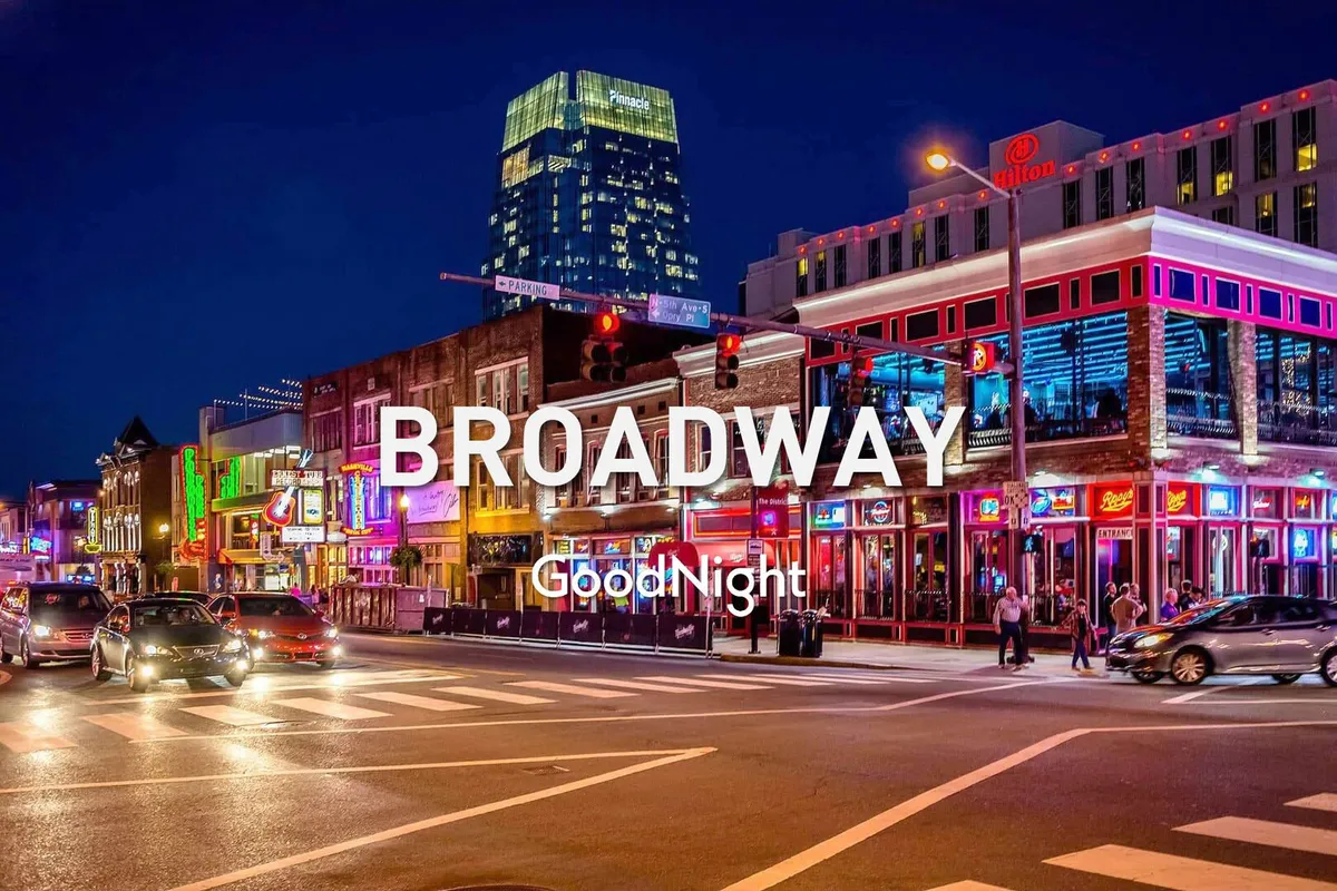 This image captures a vibrant Nashville streetscape at night, with colorful neon signs, a bustling crowd of people walking, and cars passing by. The energy and excitement of nightlife is front and center, while the visual cues evoke both music and entertainment districts central to Nashville’s identity.