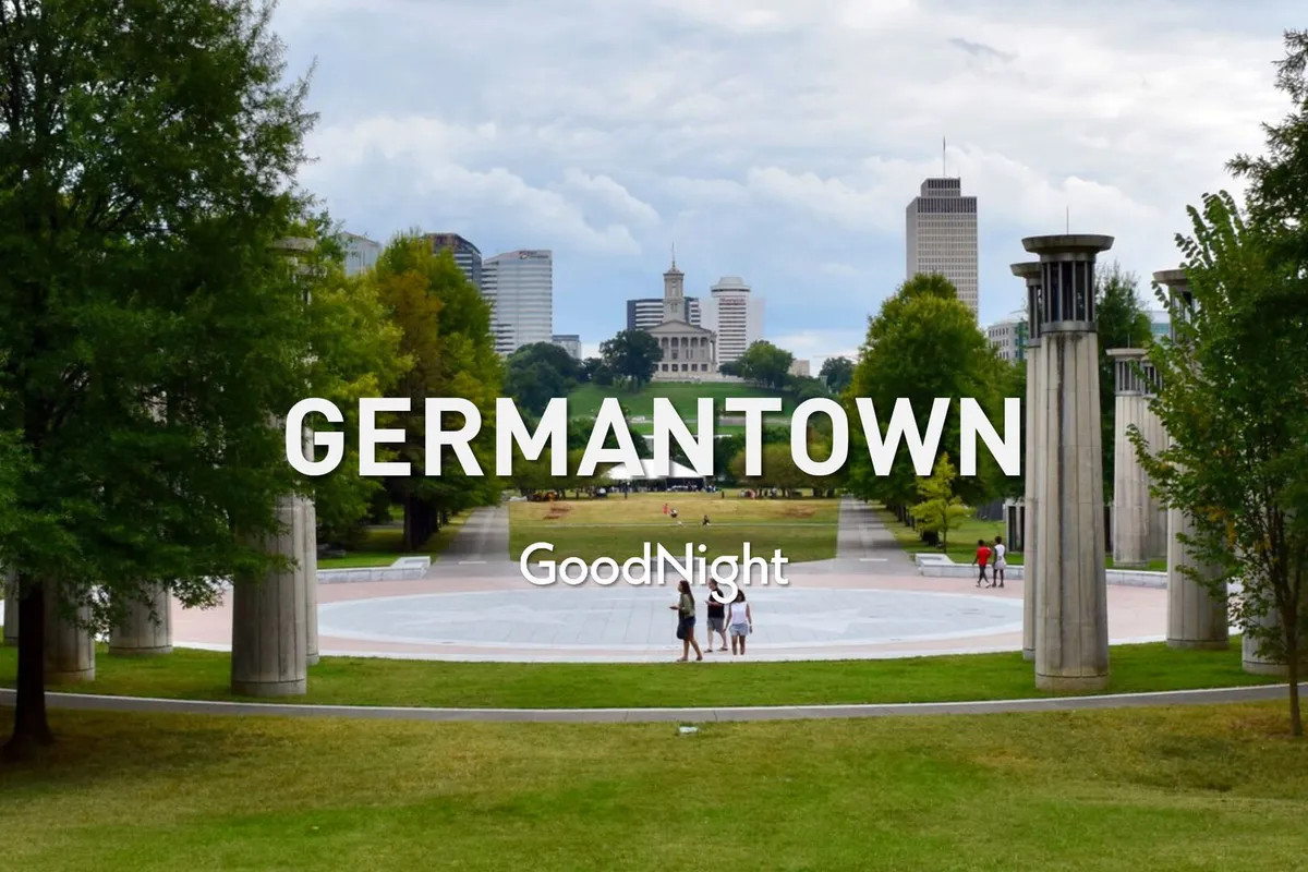 A calming view of the Germantown skyline framed by a green park area, stone pillars, and people walking. The setting suggests a peaceful outdoor environment ideal for relaxing strolls or al fresco gatherings.