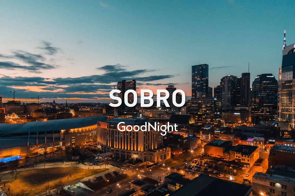 A sweeping view of the city skyline at sunset, with the warm glow of building lights beginning to illuminate the horizon. The vantage point suggests an elevated perspective, echoing the feeling of being above the city, perfect for rooftop relaxation.