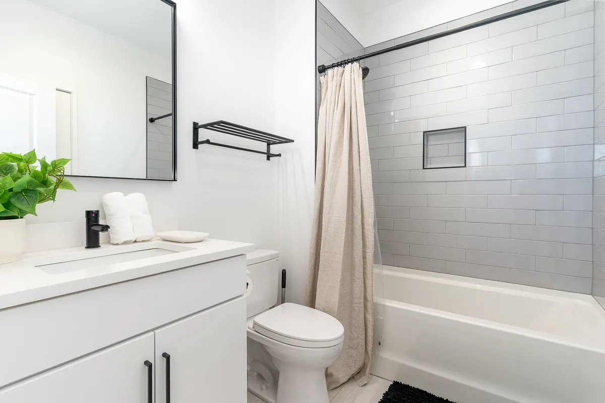 This image features a modern vanity with a sink, a shower area, and a mirror, capturing a clean and thoughtfully designed utility space. The setting is bright, organized, and hints at contemporary conveniences in everyday routines.