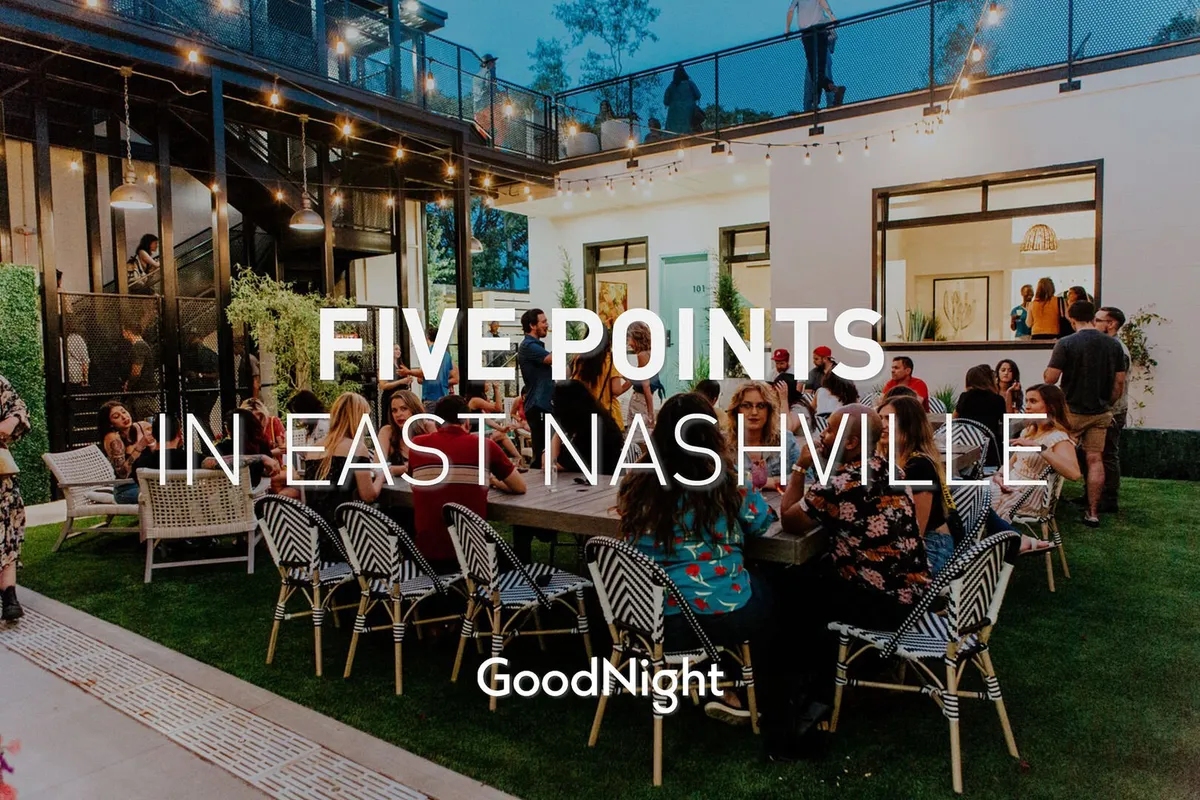 The image captures an outdoor dining and socializing area lit by string lights, surrounded by modern architecture and groups of people enjoying each other’s company. The bistro lighting and lively ambiance suggest evening gatherings and festive occasions.