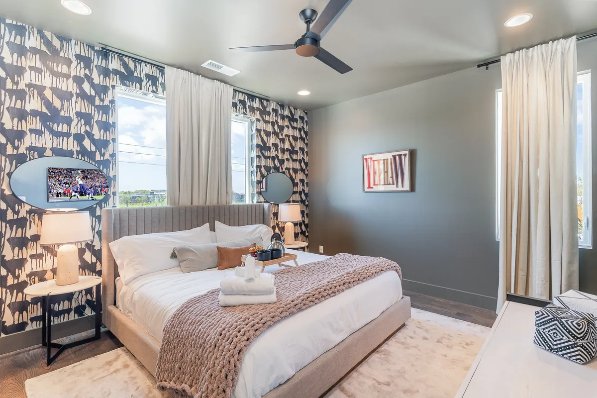 A stylish bedroom with plush bedding, animal print accents, chic lighting, and mirrors. The room feels inviting, well-organized, and ready for guests seeking comfort and streamlined routines.